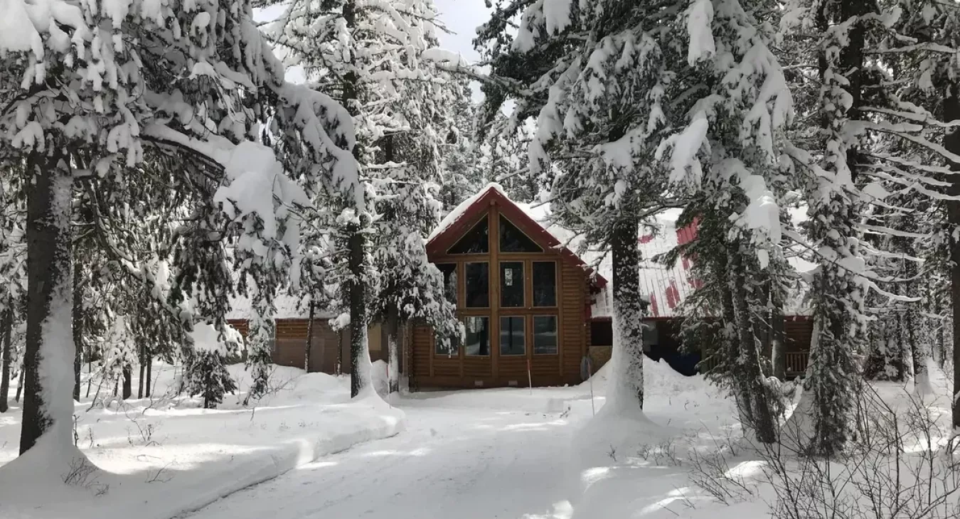 Yellowstone Log Cabin surrounded by snow-covered pines in Island Park Idaho winter