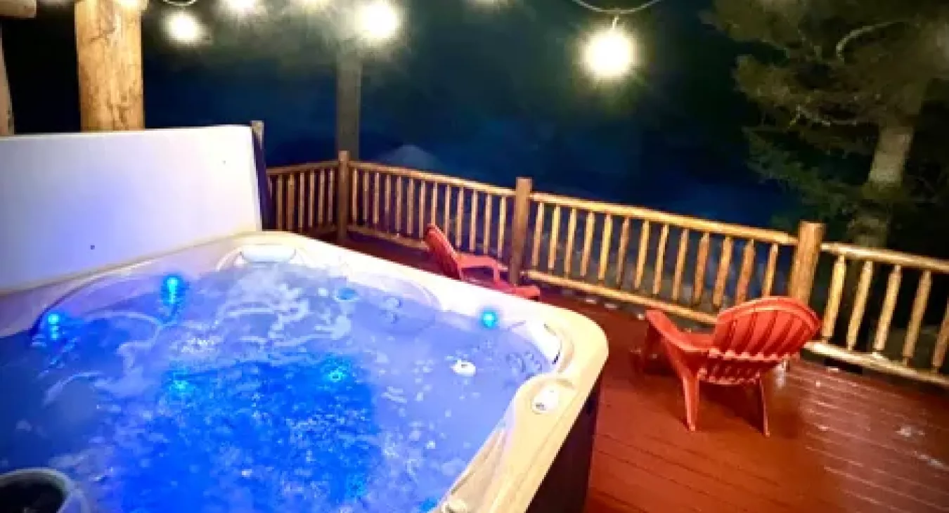 Private outdoor hot tub with string lights and mountain views at Yellowstone Log Cabin Island Park