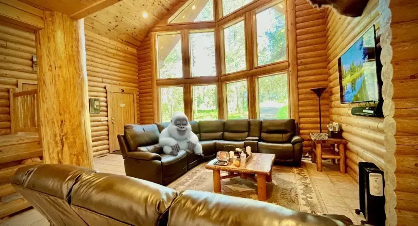Spacious log cabin great room with floor-to-ceiling windows and rustic decor near Yellowstone National Park