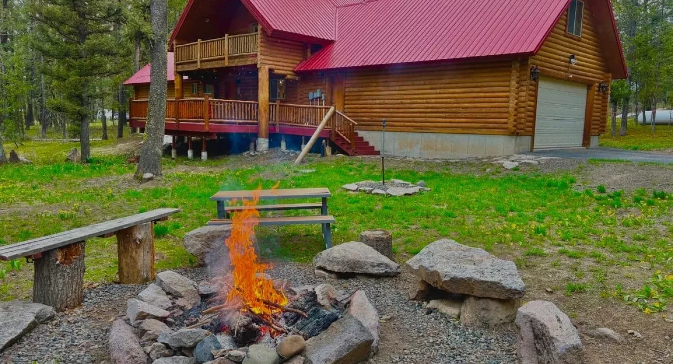 Outdoor fire pit with roaring fire in front of Yellowstone Log Cabin Island Park Idaho