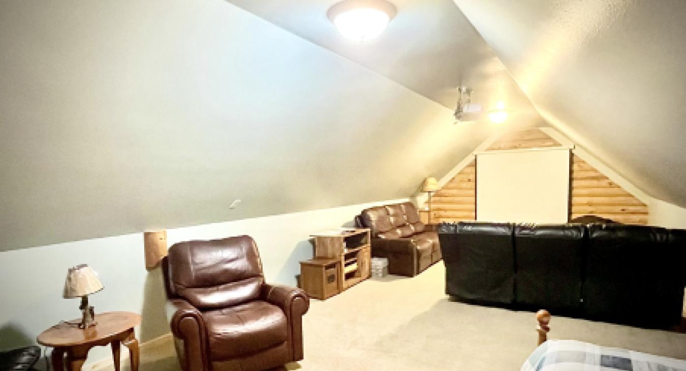 Upstairs media room with projector screen recliners and sectional sofa at Yellowstone Log Cabin Island Park