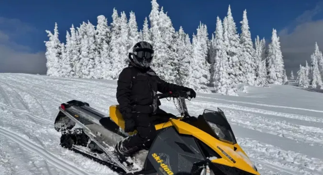 Snowmobiler on groomed trail surrounded by snow ghost trees near Island Park Idaho and Yellowstone