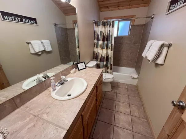 Second bathroom with tub shower combo and vanity at Yellowstone Log Cabin Island Park Idaho